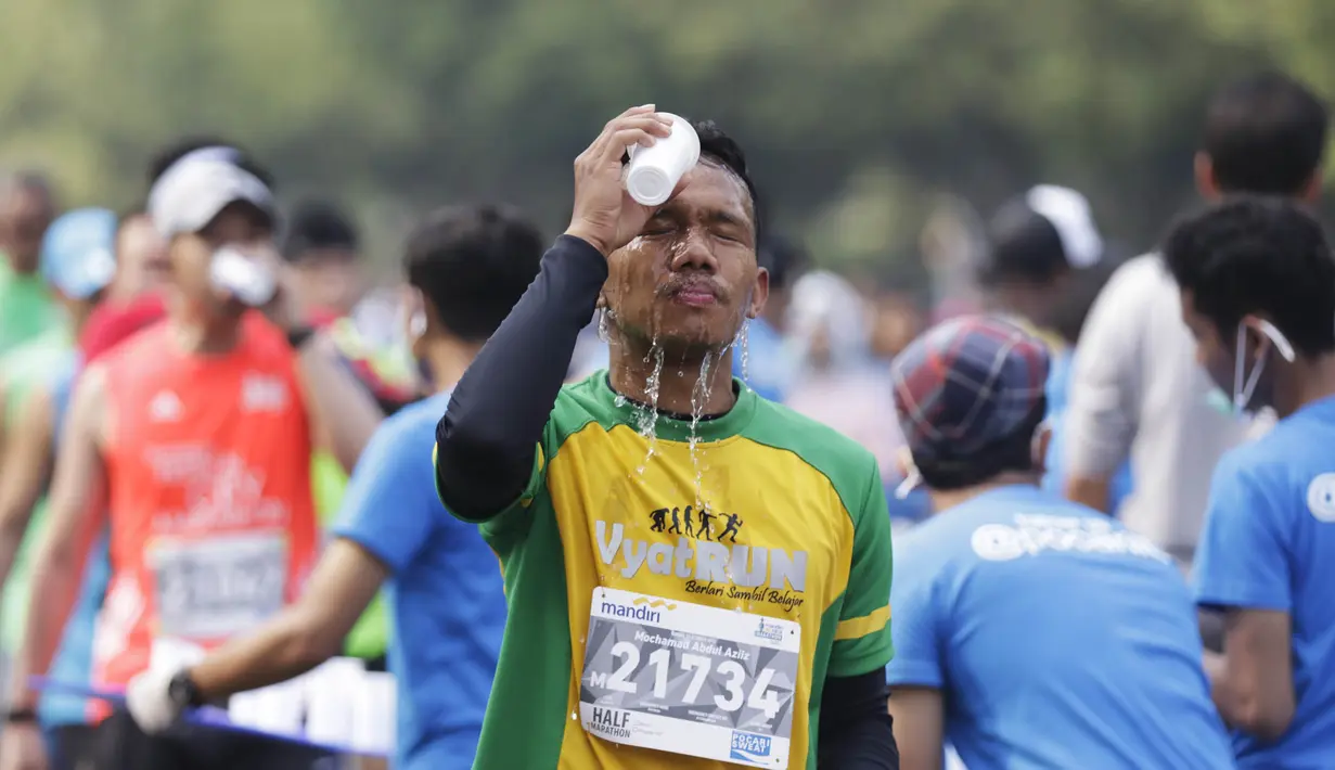 Seorang pelari mengguyur wajahnya dengan air saat mengikuti Mandiri Jakarta Marathon. (Bola.com/Vitalis Yogi Trisna)