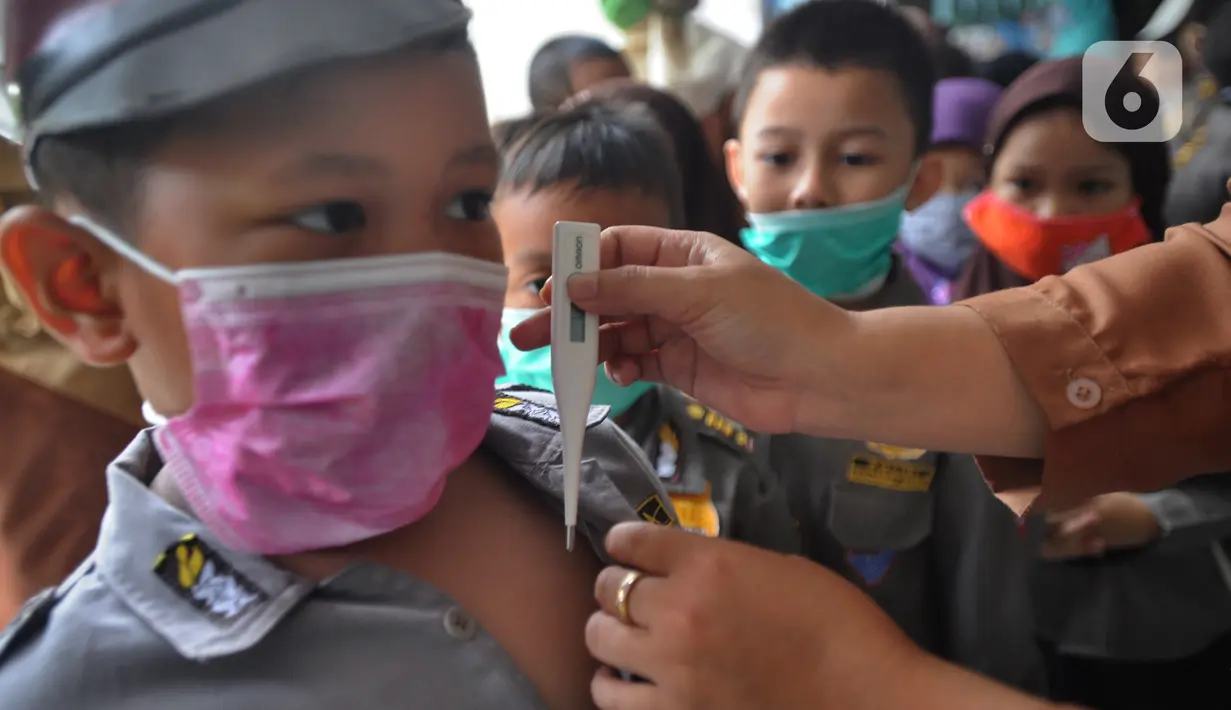 Guru memeriksa suhu tubuh seorang murid di  Taman Kanak-kanak (TK) RA Hidayatusshibyan Cinere, Depok, Kamis (5/3/2020). Mengantisipasi virus corona COVID-19, murid-murid diukur suhu tubuhnya  dan diwajibkan mencuci tangan mereka sebelum masuk kelas.  (merdeka.com/Arie Basuki)