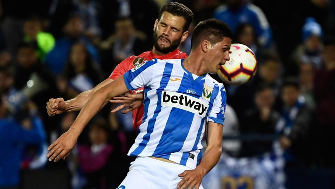 Pemain Leganes, Guido Carrillo berebut bola dengan bek Real Madrid, Nacho Fernandez dalam lanjutan La Liga 2018-2019 di Estadio Municipal Butarque, Senin (15/4). Real Madrid hanya mampu meraih hasil imbang 1-1 saat bertandang ke markas Leganes. (PIERRE-PHILIPPE MARCOU / AFP)