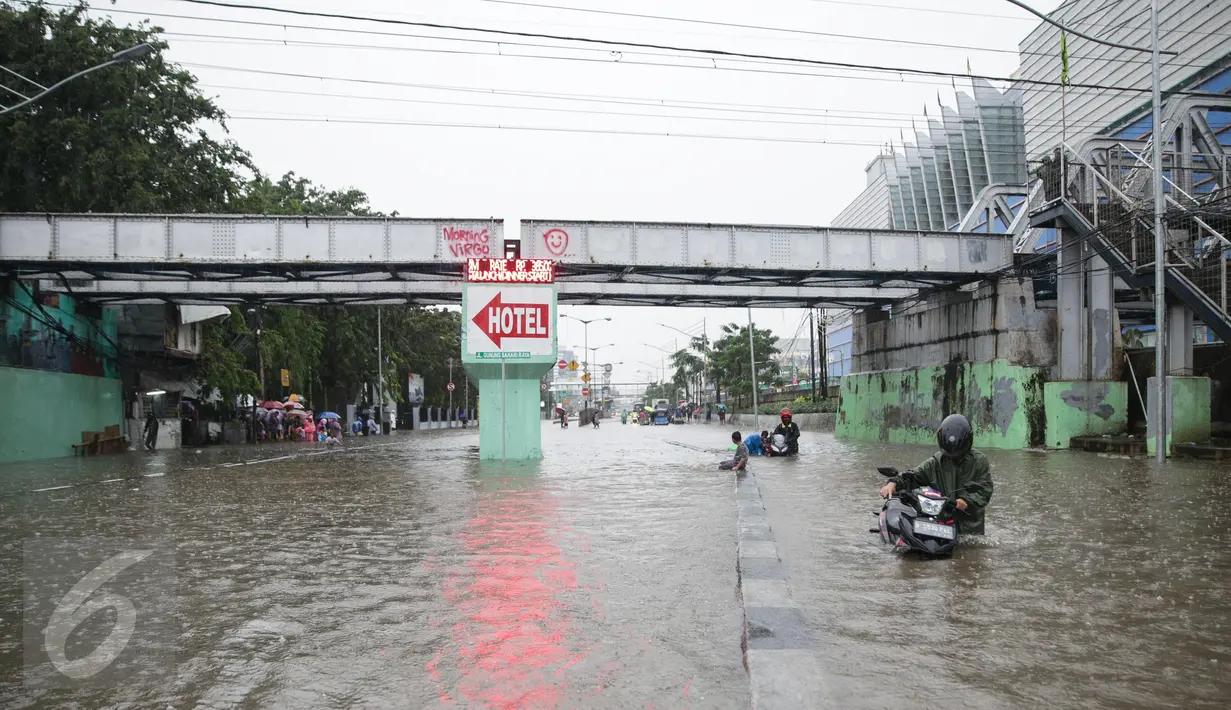 Seorang pria mendorong motornya yang mogok saat menerobos banjir di Jalan Gunung Sahari, Jakarta Pusat, Selasa (21/2). Banjir setinggi pinggang orang dewasa menyebabkan terputusnya sejumlah akses jalan untuk kendaraan bermotor (Liputan6.com/Faizal Fanani)