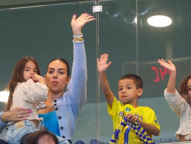 Georgina Rodriguez dan buah hati dari pasangan pemain Al Nassr Cristiano Ronaldo saat menghadiri pertandingan antara Al Nassr melawan Al Riyadh dalam laga pekan ke-16 Saudi Pro League 2023/2024 yang digelar di Al Awwal Park, Sabtu (9/12/2023) dini hari WIB. (AFP/Fayez Nureldine)