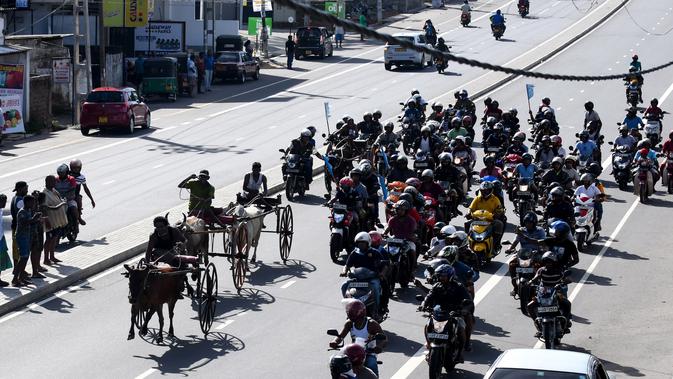 Para pengendara sepeda motor ikut mengikuti dari belakang saat para ppeserta memacu tunggangannya dalam perlombaan balap gerobak sapi di Kolombo, Sri Lanka, Sabtu (20/4). (LAKRUWAN WANNIARACHCHI/AFP)