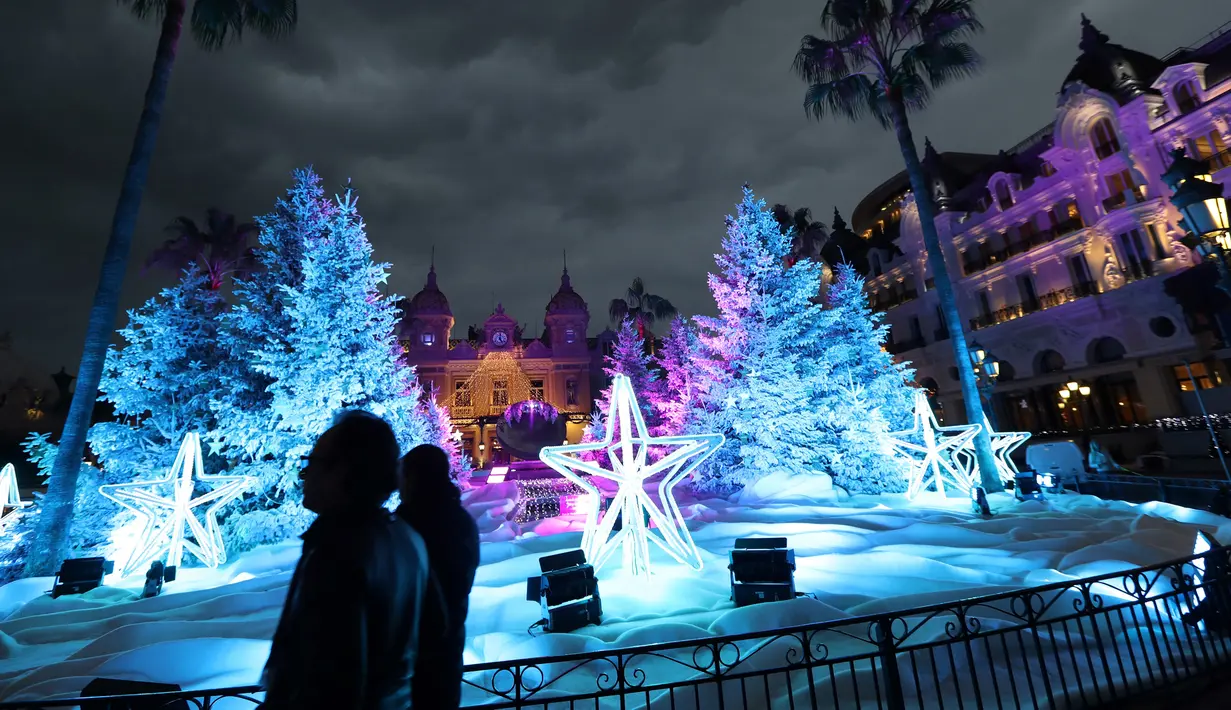 Orang-orang mengunjungi lampu dan dekorasi untuk menyambut Natal yang menghiasi depan Kasino Monte-Carlo di Monako pada 7 Desember 2018. (Photo by VALERY HACHE / AFP)