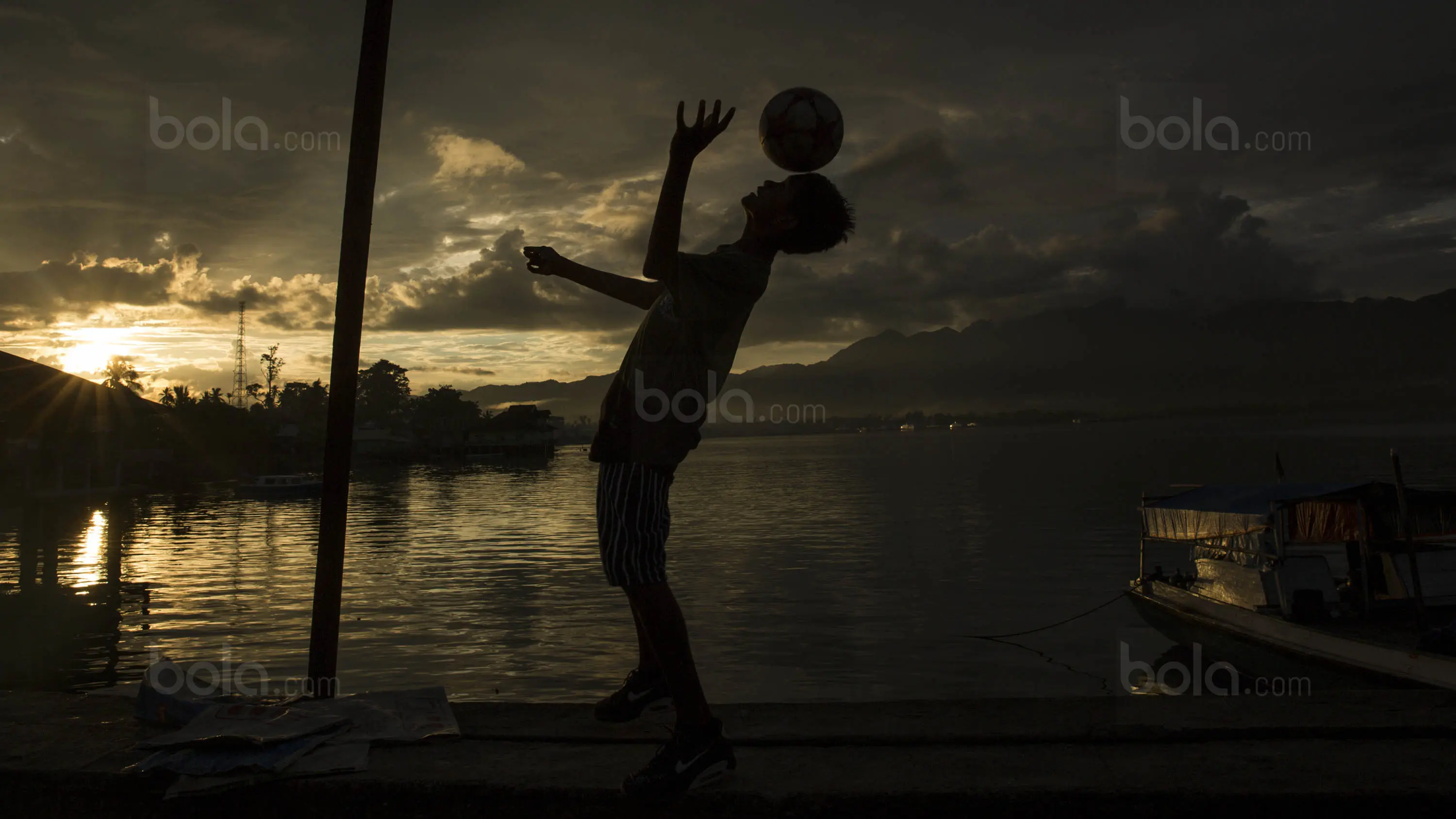 Pesepak bola SSB Tulehu Putra, Ilham Lestaluhu bermain bola di tepi Pelabuhan Tulehu. (Bola.com/Vitalis Yogi Trisna)