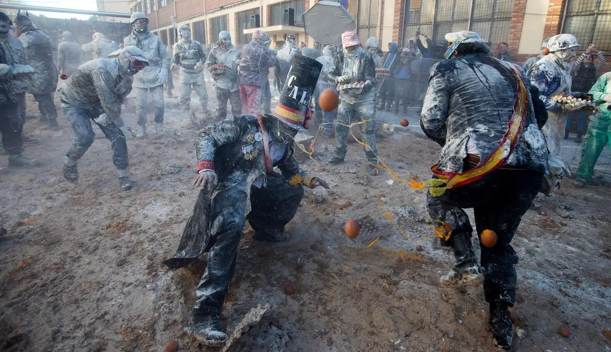 Orang-orang yang bersuka ria mengenakan pakaian militer tiruan saat ikut serta dalam perang makanan "Els Enfarinats" di Kota Ibi, Spanyol, 28 Desember 2022. 
Festival tradisional ini sudah berlangsung selama 200 tahun. (JAIME REINA/AFP)
