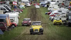 Mobil-mobil melewati kamp selama pertemuan dunia Citroen 2CV Friends di dekat Delemont, Swiss, 26 Juli 2023. (GABRIEL MONNET/AFP)