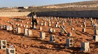 Seorang pria berjalan melewati makam korban banjir bandang di Derna, Libya, Jumat (15/9/2023). Jumlah korban tewas di kota pesisir Derna telah melonjak hingga lebih dari 10 ribu orang ketika upaya pencarian terus dilakukan menyusul banjir besar yang diakibatkan oleh jebolnya dua bendungan saat hujan lebat, kata Bulan Sabit Merah Libya pada Kamis. (AP Photo/Yousef Murad)