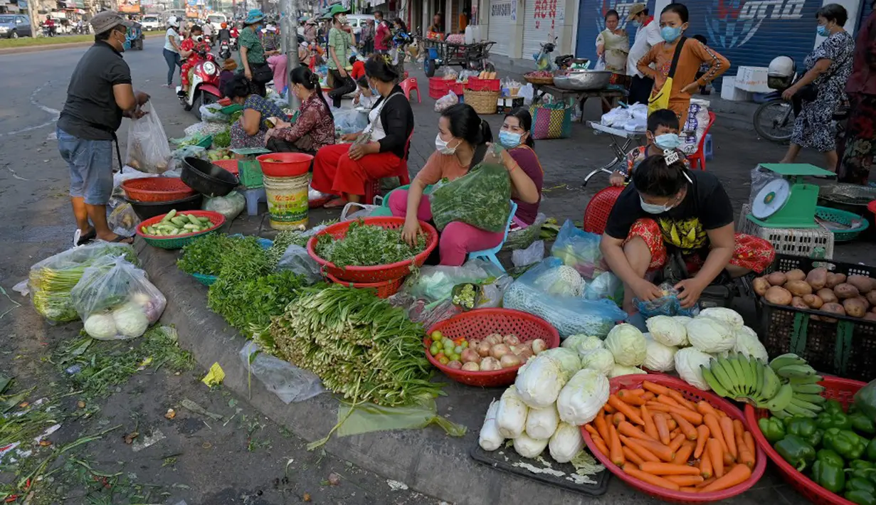 Pedagang menyiapkan sayuran untuk dijual di sepanjang jalan karena pasar tetap tutup di tengah pembatasan lockdown yang diberlakukan untuk mencoba menghentikan lonjakan kasus virus corona COVID-19 di Phnom Penh, Kamboja, Selasa (11/5/2021). (TANG CHHIN Sothy/AFP)