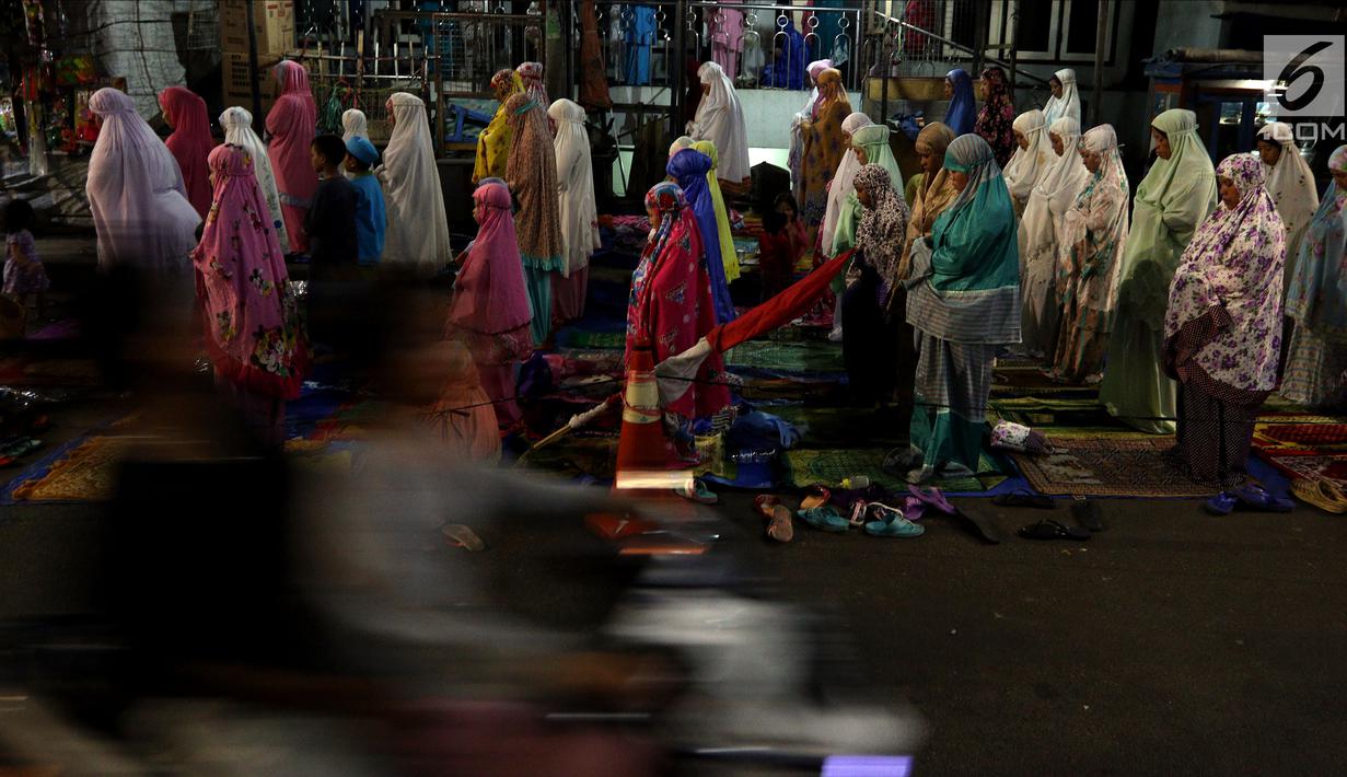Jemaah melaksanakan salat tarawih hingga ke badan jalan akibat melubernya Musala Miftahul Jannah di Kawasan Pasar Gembrong, Jakarta, Kamis (17/5). (Liputan6.com/JohanTallo)
