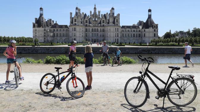 Pengendara sepeda mengunjungi Kastil Chambord, di Chambord, Prancis pada 22 Juli 2020. Bangunan bersejarah ini merupakan salah satu kastil terbesar di Prancis sekaligus lokasi nyata yang menginspirasi film pertama Beauty and The Beast, 26 tahun lalu. (Photo by Ludovic MARIN / AFP)