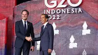 Perdana Menteri Belanda Mark Rutte (kiri) berjabat tangan dengan Presiden Indonesia Joko Widodo  atau Jokowi yang menyambutnya pada hari pertama Konferensi Tingkat Tinggi (KTT) G20 di Nusa Dua, Bali, Selasa (15/11/2022) pagi. Setidaknya total 17 kepala negara G20 akan menghadiri KTT dua hari ini. (KEVIN LAMARQUE / POOL / AFP)