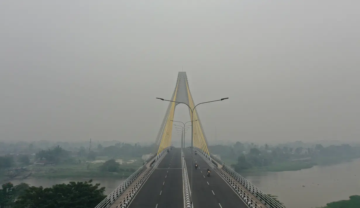 Gambar udara menunjukkan sebuah jembatan ketika kabut asap pekat menyelimuti Pekanbaru, Riau, Minggu (15/9/2019). Kabut asap yang menyelimuti Kota Pekanbaru makin pekat akibat kebakaran hutan dan lahan di Riau, Jambi, serta Sumatera Selatan. (ADEK BERRY/AFP)