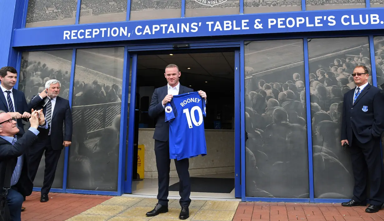 Penyerang baru Everton Wayne Rooney, memegang kostum tim barunya setelah konferensi pers di Goodison Park di Liverpool (10/8). Rooney mengawali karier bersama Everton pada 1996 dan masuk skuad utama pada 2002. (AFP Photo/Paul Ellis)
