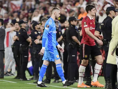 Pemain Manchester United, David De Gea dan Harry Maguire meninggalkan lapangan setelah ditaklukkan Sevilla pada leg kedua perempat final di Ramon Sanchez Pizjuan, Jumat (21/4/2023). Kedua pemain ini menjadi sorotan lantaran menjadi biang kerok kekalahan Setan Merah. (AFP/Cristina Quicler)