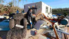 Jaquish Fox (10) membantu bibinya menyelamatkan barang yang masih bisa dipakai setelah tornado menghantam Holly Springs, Mississipi, Kamis (24/12). Badai tornado menerjang wilayah Amerika Serikat bagian selatan dan menewaskan 11 orang.  (REUTERS)