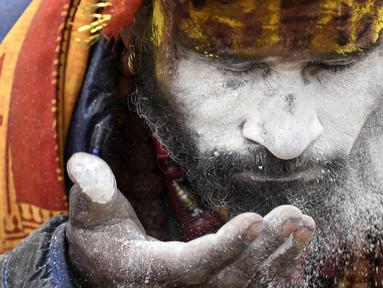 Seorang Sadhu (orang suci Hindu) mengoleskan wajahnya di dekat kuil Pashupatinath pada malam festival Hindu Maha Shivaratri di Kuil Pashupatinath di Kathmandu (20/2/2020). Maha Shivaratri, sebuah festival Hindu yang dirayakan sebelum kedatangan musim semi. (AFP/Prakash Mathema)
