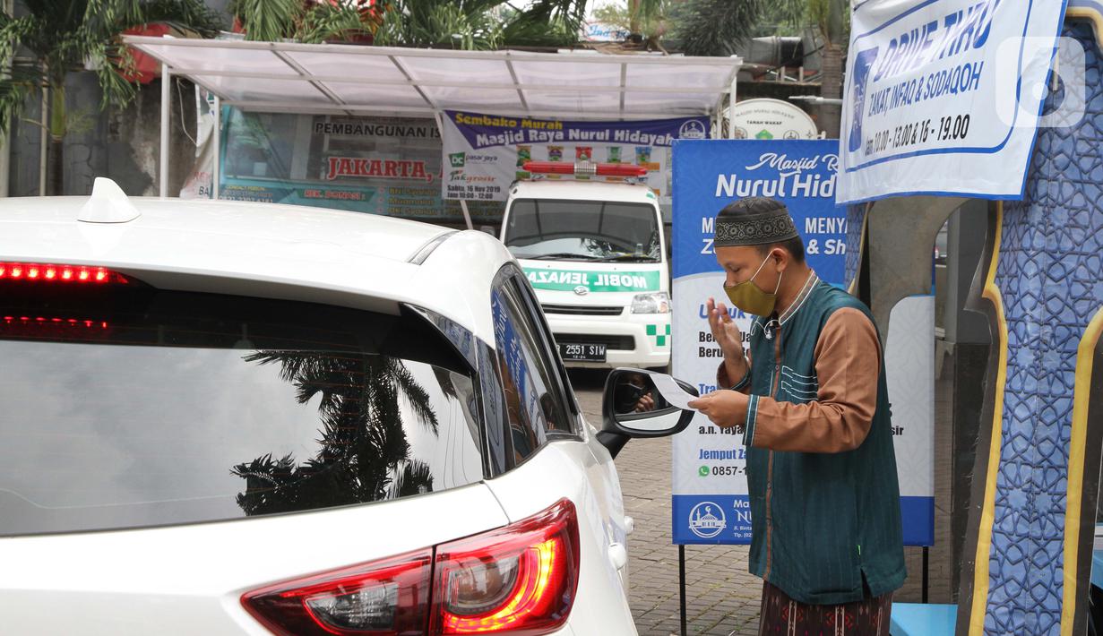 Petugas Amil Zakat melayani warga yang membayar zakat fitrah melalui sistem "drive thru" di Masjid Nurul Hidayah, Tanah Kusir, Jakarta, Selasa (19/5/2020). Layanan zakat "drive thru" selama pandemi COVID-19 ini diberlakukan dengan protokol kesehatan dan keselamatan. (Liputan6.com/ Johan Tallo)