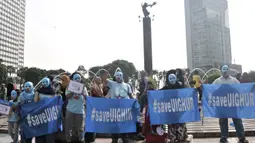 Warga mengenakan topeng bendera Turkestan Timur dan membentangkan poster saat menggelar Aksi Save Uighur selama Hari Bebas Kendaraan Bermotor (HBKB) atau Car Free Day (CFD), Jakarta, Minggu (22/12/2019). (merdeka.com/Iqbal S. Nugroho)