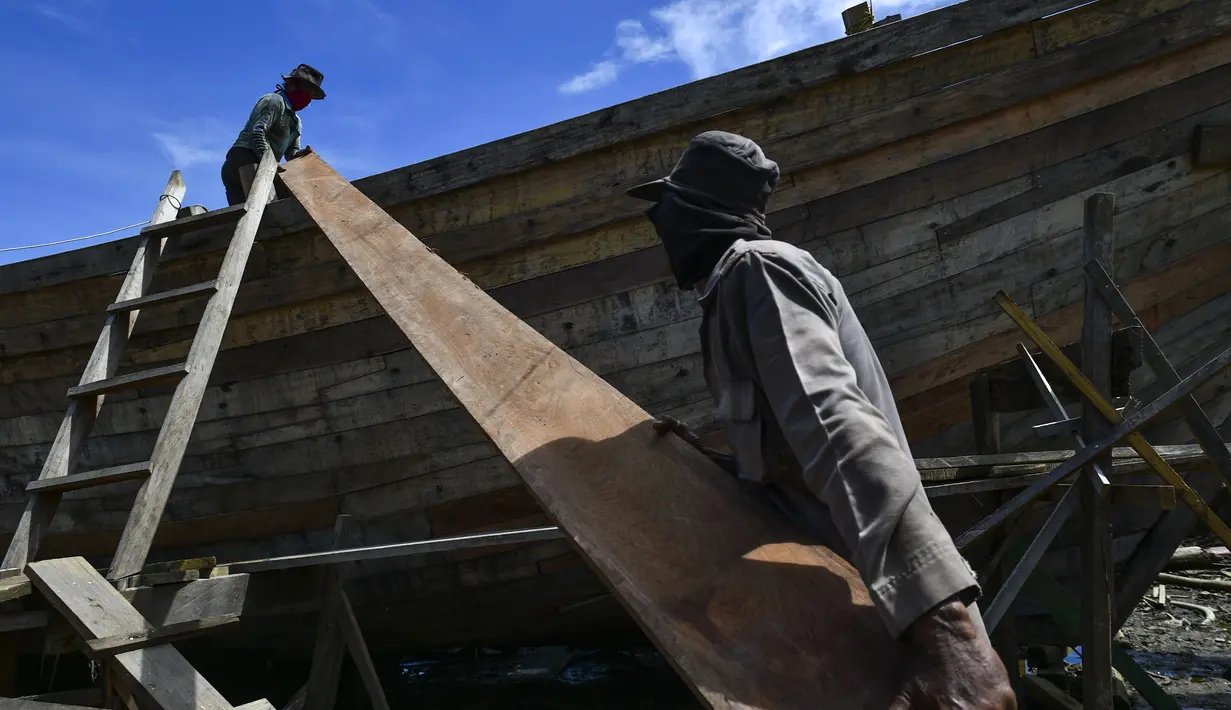 Pekerja memuat material untuk membuat kapal nelayan di Banda Aceh, Aceh pada 21 November 2020. Industri galangan kapal tradisional di daerah itu mengalami kesulitan memperoleh bahan baku kayu untuk memproduksi kapal nelayan, sehingga berdampak pada proses penyelesaian kapal. (CHAIDEER MAHYUDDIN/AFP)