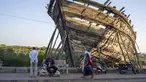 Seorang pedagang kaki lima duduk di bangku umum di depan haluan kapal tradisional yang sedang dibangun di Mandvi di Gujarat, India, Selasa (9/1/2024). (AP Photo/Ashwini Bhatia)