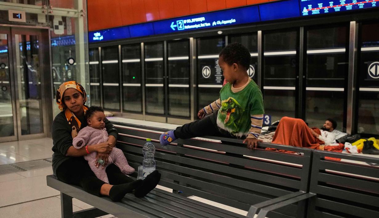 Warga yang mengungsi membawa kasur, bantal, makanan ringan, hingga hewan peliharaan ke dalam area stasiun untuk bertahan selama serangan berlangsung. Tampak dalam foto, orang-orang berlindung di stasiun metro bawah tanah saat sirene serangan udara memperingatkan datangnya rudal Iran di Tel Aviv, Israel, Sabtu, 7 Maret 2026. (AP Photo/Ohad Zwigenberg)