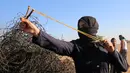 Pengunjuk rasa wanita Palestina menembakkan batu menggunakan ketapel ke arah tentara Israel saat bentrok di Khan Younis, perbatasan Gaza, Jumat (10/8). Dua warga Palestina, termasuk seorang medis, tewas oleh tembakan tentara Israel. (SAID KHATIB/AFP)