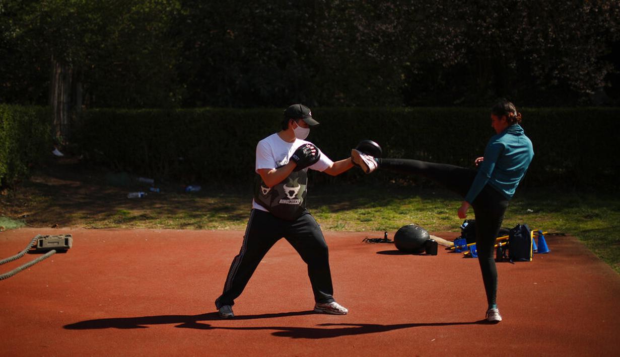 Pelatih bela diri mengenakan masker untuk mencegah penyebaran COVID-19 saat melatih murid-muridnya di Taman Cinquantenaire, Brussel, Belgia, Senin (29/3/2021). Belgia kembali memberlakukan lockdown ketat sebagai tanggapan atas lonjakan infeksi COVID-19 yang mengkhawatirkan. (AP Photo/Francisco Seco)