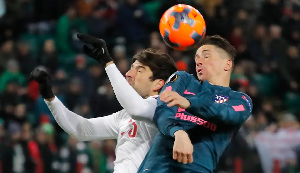 Pemain Lokomotiv Moskow, Vedran Corluka berebut bola dengan pemain Atletico Madrid Fernando Torres pada leg kedua babak 16 besar Liga Europa di RZD Arena, Kamis (15/3). Atletico Madrid lolos ke perempatfinal usai menang telak 5-1. (AP/Pavel Golovkin)