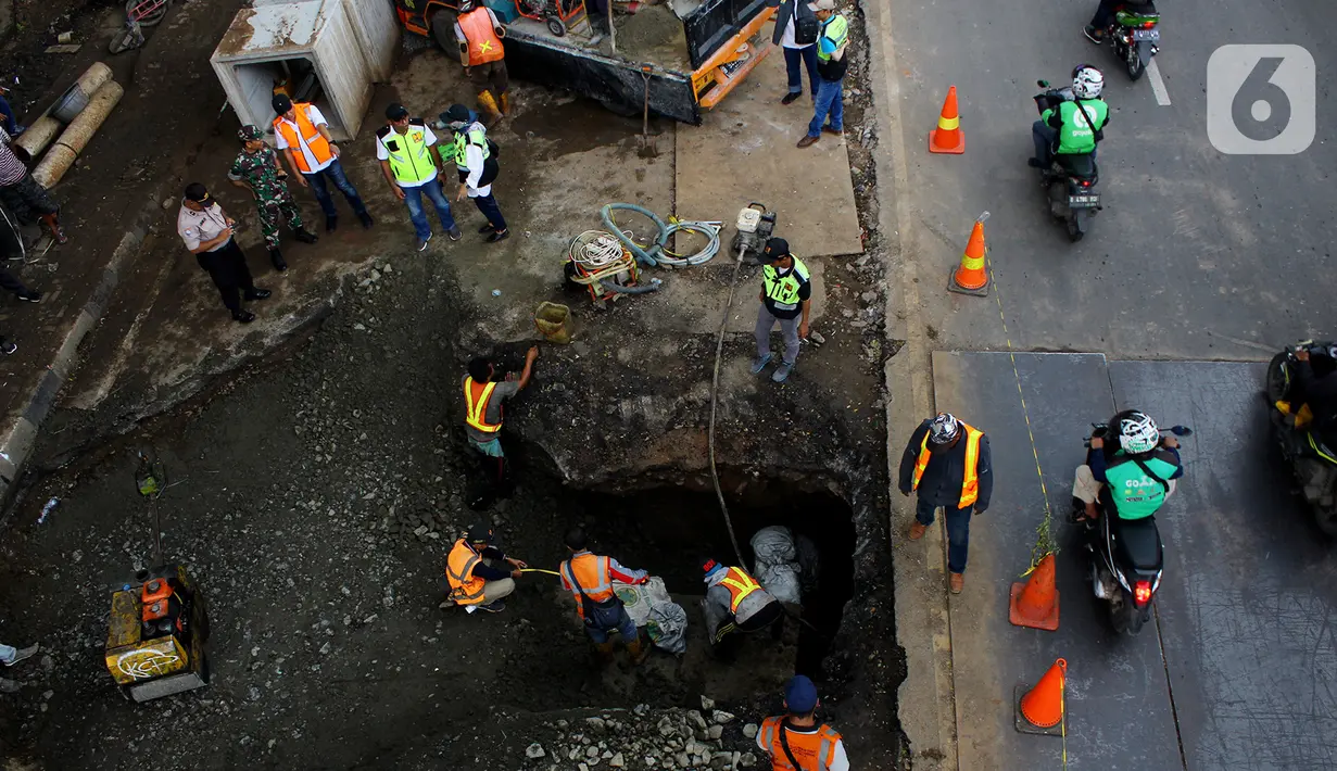 Pengendara melintas dekat perbaikan jalan ambles di Jalan Daan Mogot, Tangerang, Senin (13/1/2020). Amblesnya jalan penghubung ke Jakarta ini diduga karena adanya kebocoran pipa PDAM Tirta Kerta Raharja milik Pemkab Tangerang yang mengikis struktur tanah. (merdeka.com/Magang/Muhammad Fayyadh)
