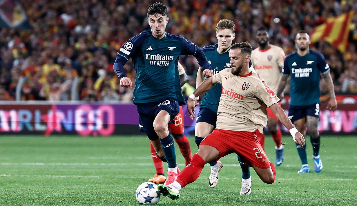 Pemain RC Lens, Jonathan Gradit, berusaha menghentikan pergerakan pemain Arsenal, Kai Havertz, pada laga Liga Champions di Stade Bollaert-Delelis, Rabu (4/10/2023). (AFP/Sameer Al-Doumy)