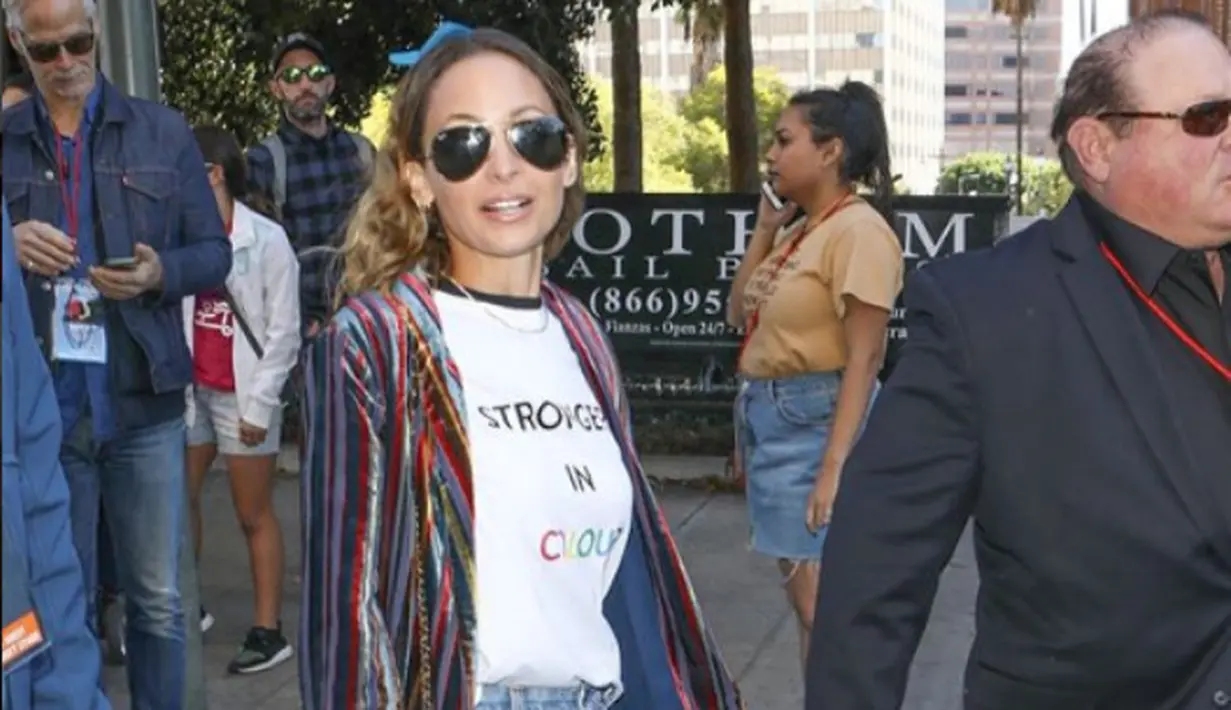 Nicole Richie mengenakan kaos bertuliskan "Stronger is Colour" yang dipadukan dengan blazer garis-garis berwarna-warni. Tampilan Nicole Richie memiliki kesan maskulin dengan jeans dan boots (instagram/justjared)