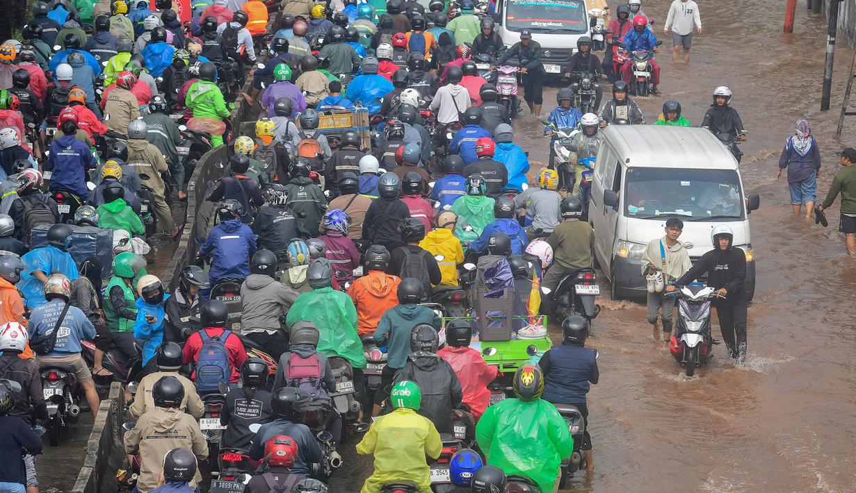 Kondisi ini disebabkan oleh curah hujan lebat yang disertai angin kencang sejak tengah malam tadi hingga meluapnya aliran Kali Mookervart. Tampak dalam foto, antrean pengendara motor yang mencoba menerobos banjir di Jalan Daan Mogot, Jakarta, Jumat (23/1/02026). (merdeka.com/ Arie Basuki)