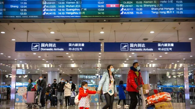 Penerbangan dari Wuhan Ditutup: Pelancong berjalan melintasi papan informasi tentang penerbangan dari Wuhan telah dibatalkan di Bandara Internasional Ibu Kota Beijing pada Kamis (23/1/2020).