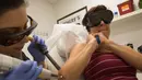 Jill Crenshaw menahan panas dan sakit ketika tato pada lengan kanannya dihapus menggunakan laser di klinik Dr. Tatoff, California, Rabu (11/5). Dengan metode laser tato tidak langsung hilang, namun hanya memudar. (AFP PHOTO/DAVID McNew)