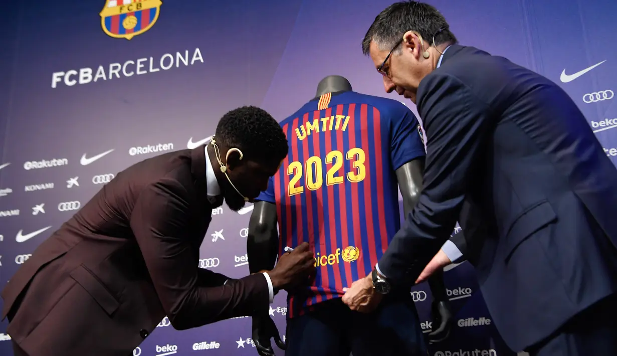 Bek asal Prancis, Samuel Umtiti menandatangani jerseynya disaksikan Presiden Barcelona FC, Josep Maria  pada pengumuman perpanjangan kontraknya di Camp Nou, Senin (4/6). Umtiti memperpanjang kontraknya bersama Barcelona hingga 2022. (LLUIS GENE/AFP)