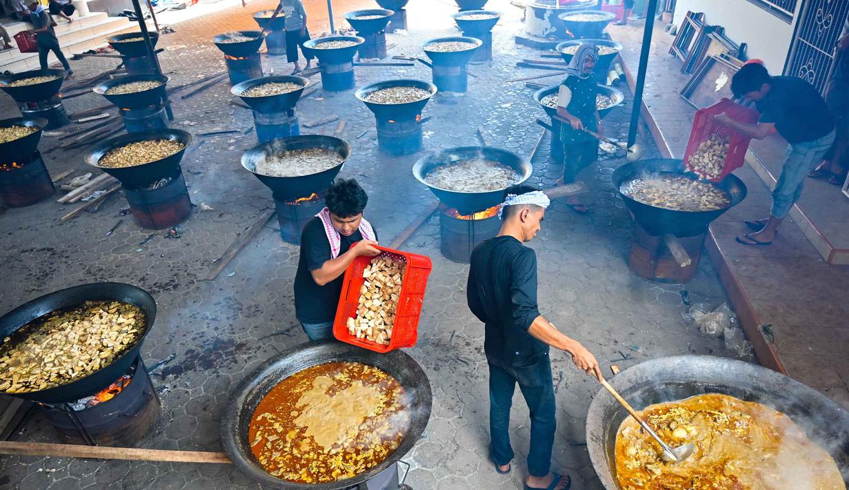 Memasak Kuah Beulangong secara massal merupakan tradisi rutin setiap pertengahan Ramadan (malam ke-17) untuk memperingati turunnya Al-Quran. Tampak dalam foto, para pria memasak hidangan kari tradisional yang disebut 'kuah beulangong' untuk dibagikan saat berbuka puasa, sekaligus memperingati turunnya Al-Quran selama bulan suci Ramadan, di Banda Aceh pada Sabtu 7 Maret 2026. (CHAIDEER MAHYUDDIN/AFP)
