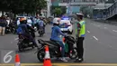 Seorang petugas polisi memberi petunjuk kepada pengendara motor saat pengalihan arus arus di kawasan Sarinah, Jakarta, Jumat (4/11). Pengalihan ini dilakukan karena beberapa titik jalan tidak bisa digunakan akibat aksi massa. (Liputan6.com/Angga Yuniar)