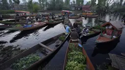 Laki-laki Kashmir menjual produk mereka di pasar sayuran terapung di Danau Dal, Srinagar, Kashmir yang dikuasai India, Kamis (7/4/2022). (AP Photo/Rajesh Kumar Singh)