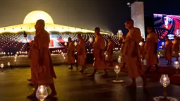 Biksu Buddha membawa lilin selama perayaan Makha Bucha di kuil Wat Dhammakaya di provinsi Pathum Thani, utara Bangkok (16/2/2022). Makha Bucha merupakan salah satu hari raya terpenting bagi para penganut agama Buddha. (AFP/Jack Taylor)