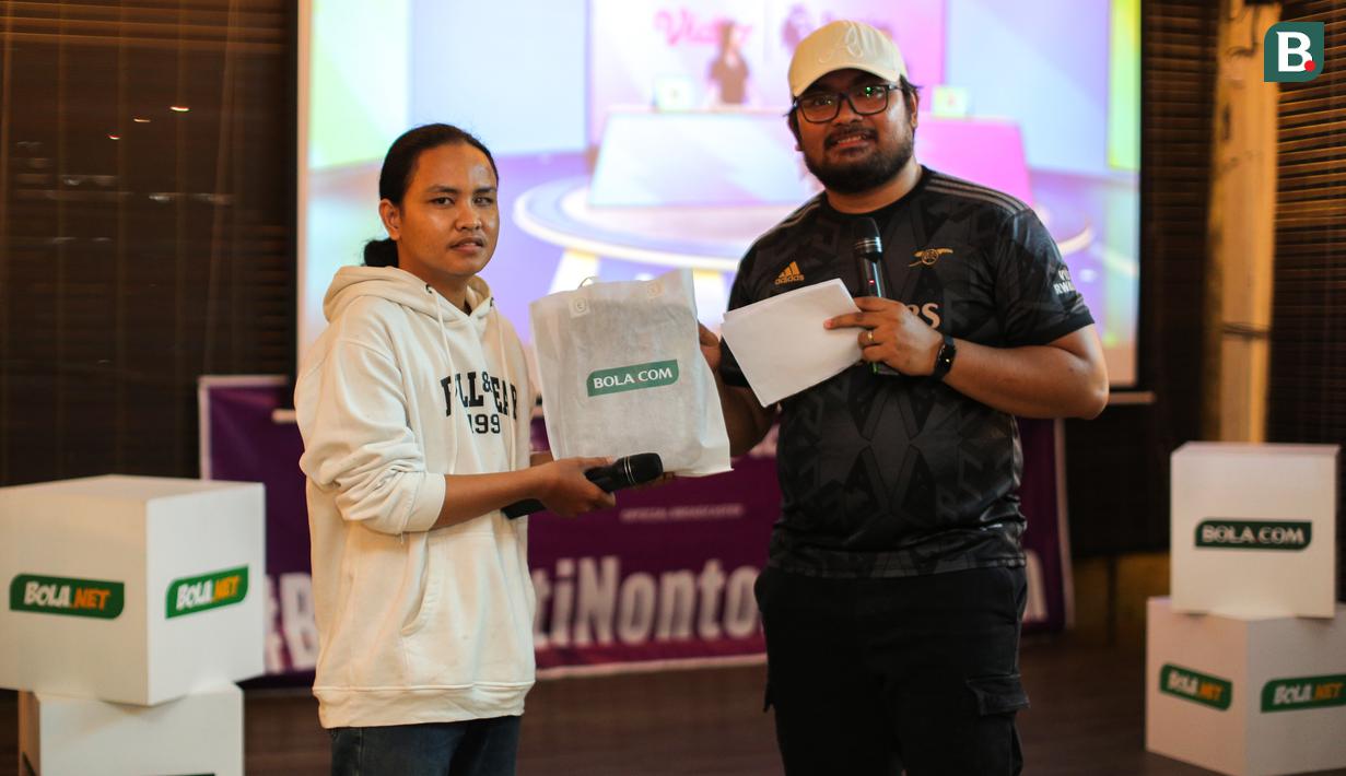Seorang pengunjung mendapatkan goodie bag setelah berhasil menjawab kuis saat Roaring Night Liga Inggris antara West Ham melawan Arsenal yang berlangsung di Triboon, Cilandak, Jakarta Selatan, Minggu (11/02/2024) malam WIB. (Bola.com/Bagaskara Lazuardi)