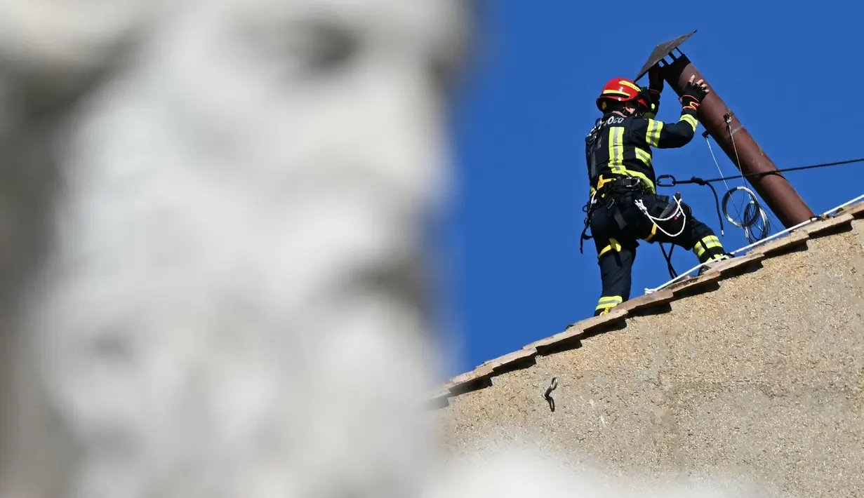 Seorang pekerja memasang cerobong asap di atap Kapel Sistina, Vatikan, pada 2 Mei 2025. (Gabriel BOUYS/AFP)