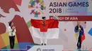 Atlet Wushu Indonesia, Lindswell Kwok (tengah) membentangkan bendera Merah Putih setelah berhasil meraih emas  pada Asian Games, Jakarta, Senin, (20/8). Lindswell berhasil menyumbang emas kedua untuk Indonesia di Asian Games 2018. (AP Photo/Aaron Favila)