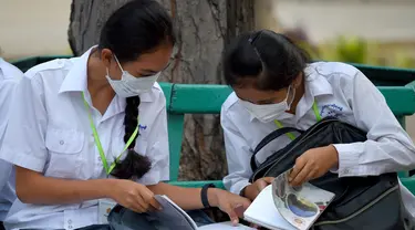Dua siswi mengenakan masker membaca buku di sebuah sekolah di Phnom Penh (28/1/2020). Kementerian kesehatan Kamboja melaporkan kasus pertama virus korona mematikan di negara itu pada 27 Januari. (TANG CHHIN SOTHY/AFP)