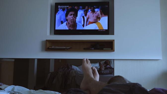 Fotografer Associated Press Rafiq Maqbool menonton film Bollywood dari televisi di sebuah kamar hotel tempat dia dikarantina, Mumbai, India, 23 April 2020. Selama beberapa hari berikutnya, kelompok WhatsApp bentukan penghuni hotel yang dikarantina menjadi keluarga barunya. (AP Photo/Rafiq Maqbool)