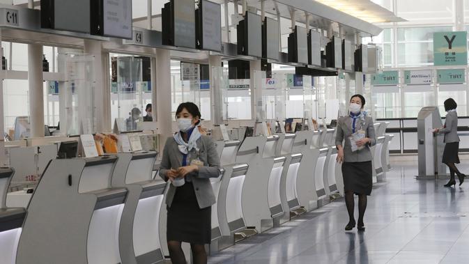 Ground staff bekerja di lobi keberangkatan Bandara Internasional Haneda yang sepi di Tokyo, Senin (28/12/2020). Jepang untuk sementara waktu melarang semua pendatang asing yang bukan penduduk masuk sebagai bentuk antisipasi varian baru COVID-19 hingga akhir Januari 2021. (AP Photo/Koji Sasahara)