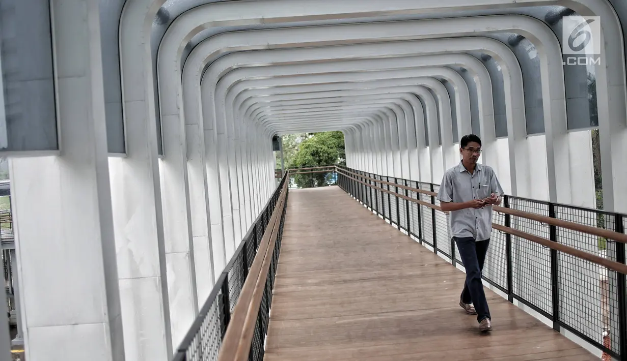 Pejalan kaki melintas di jembatan penyeberangan orang (JPO) Bundaran Senayan, Jakarta, Senin (21/1). Instalasi lampu akan menambah keindahan JPO di malam hari. (Liputan6.com/Faizal Fanani)
