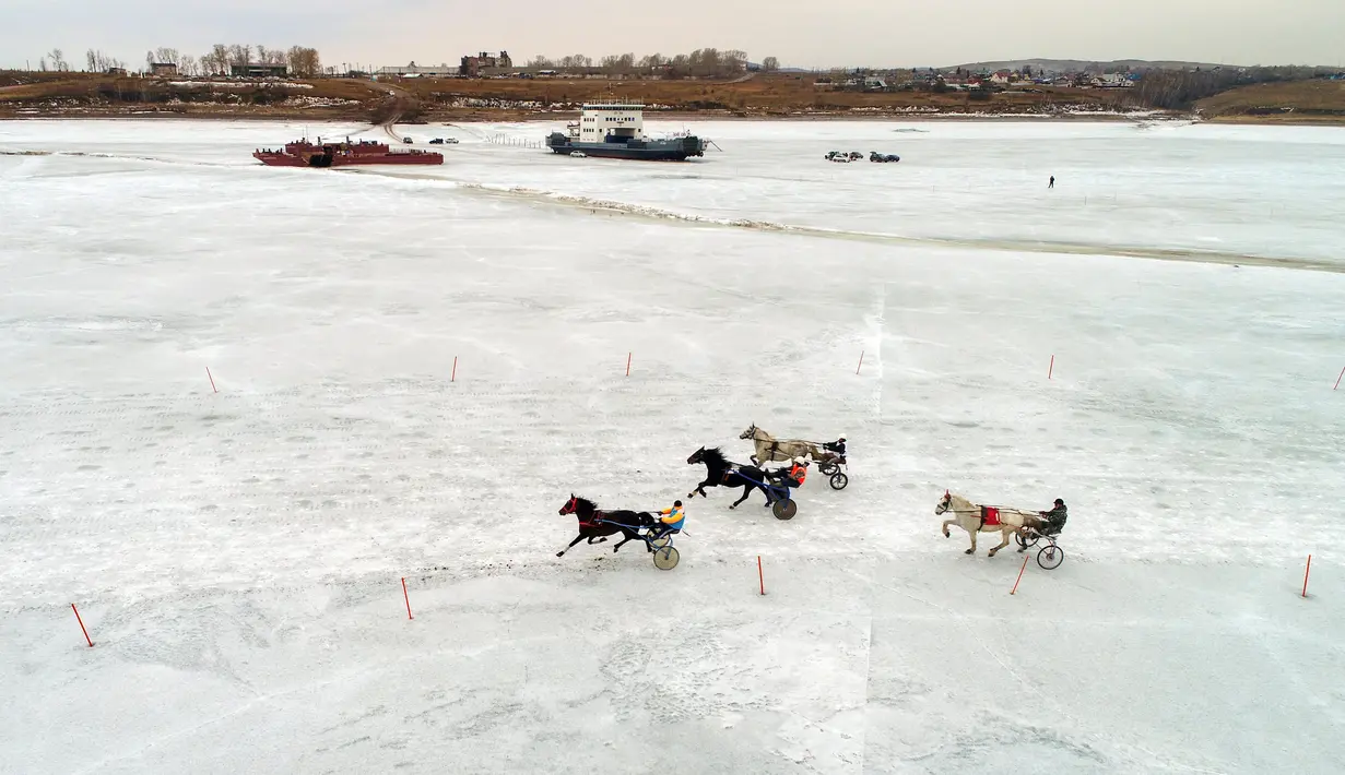 Peserta memacu troika selama bersaing dalam balapan kuda Ice Derby di Sungai Yenisei yang membeku, Krasnoyarsk, Rusia (16/3). Ice Derby merupakan kejuaraan balap kuda amatir yang berlangsung setiap akhir musim dingin. (Reuters/Ilya Naymushin)