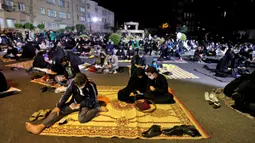 Warga Iran yang sebagian mengenakan masker menghadiri acara kajian dan pengajian Lailatul Qadar, salah satu malam paling suci selama bulan Ramadan, di luar masjid di Teheran, Rabu (13/5/2020). Pemerintah Iran membuka kembali masjid-masjid untuk manyambut malam Lailatul Qadar. (ATTA KENARE/AFP)
