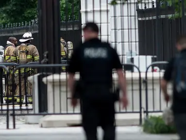 Petugas pemadam kebakaran berdiri di depan gerbang bagian utara Gedung Putih, Washington, DC, Senin (30/5). Gedung Putih ditutup sebagian untuk menyelidiki sebuah benda mencurigakan yang dilemparkan melalui pagar. (Brendan Smialowski/AFP)
