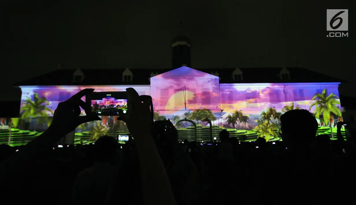 Warga mengabadikan pertunjukan projection mapping di depan area Museum Fatahillah, Jakarta, Jumat (19/1). Pertunjukan ini menandai rangkaian kegiatan perayaan 60 tahun hubungan diplomatik Indonesia-Jepang. (Liputan6.com/Helmi Fithriansyah)